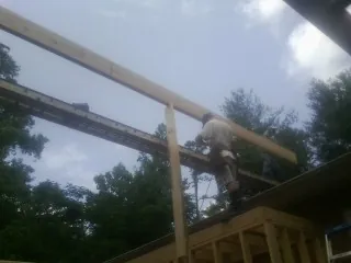 Carpenter setting a ridge beam over a new addition frame — Ice Dam Removal by Roofing Brothers in Kitty Hawk