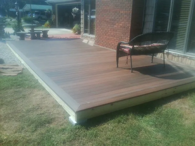 New wood deck and wicker chair beside a brick house in Kitty Hawk