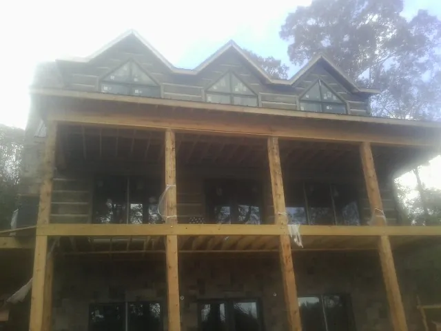 Dormers and porch framing on a large log home under construction — Roof Coating work by our crew in Kitty Hawk