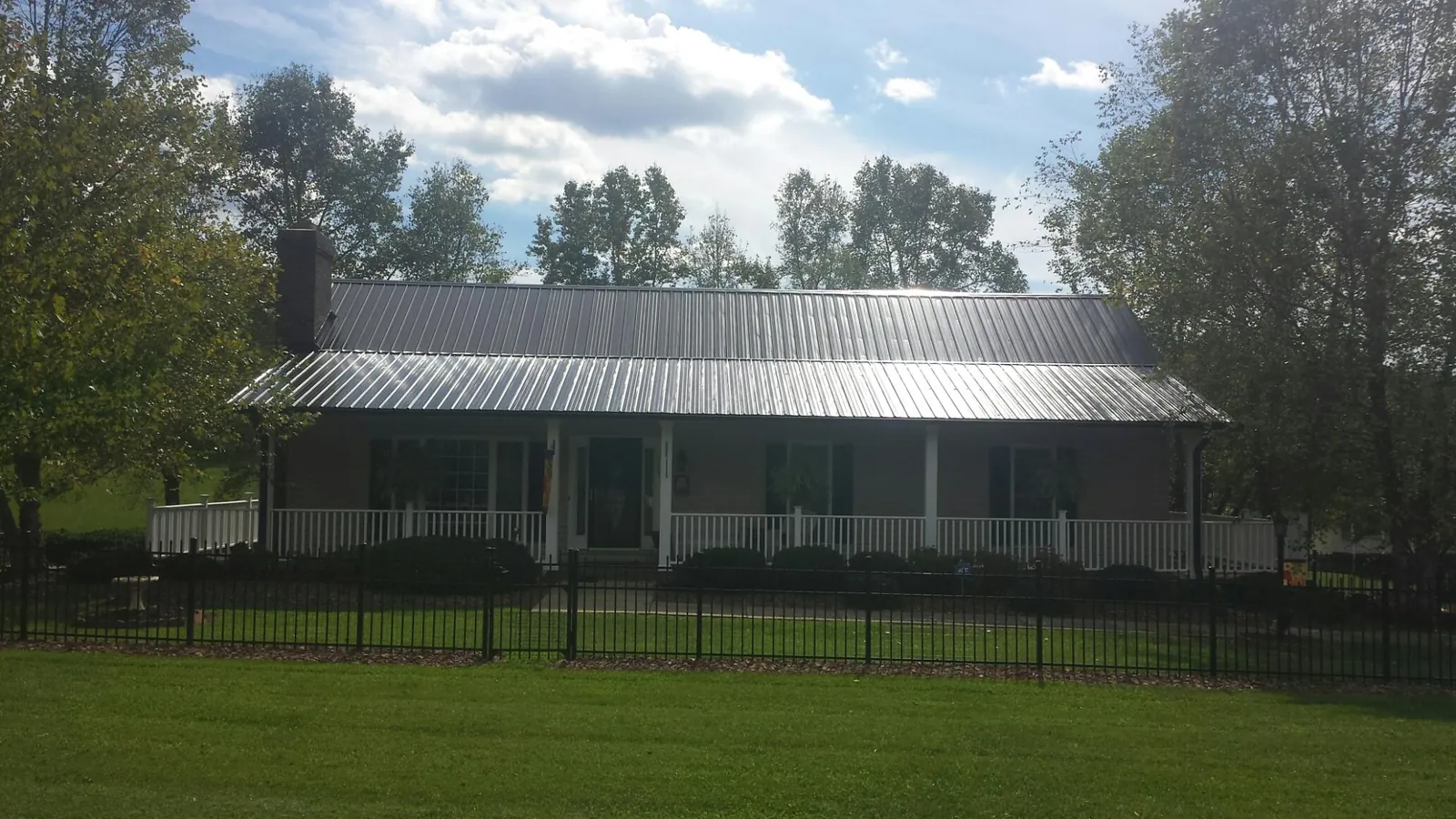 Gray metal roof on a brick ranch with a full width front porch — Gutter Guard Installation work by our crew in Kitty Hawk